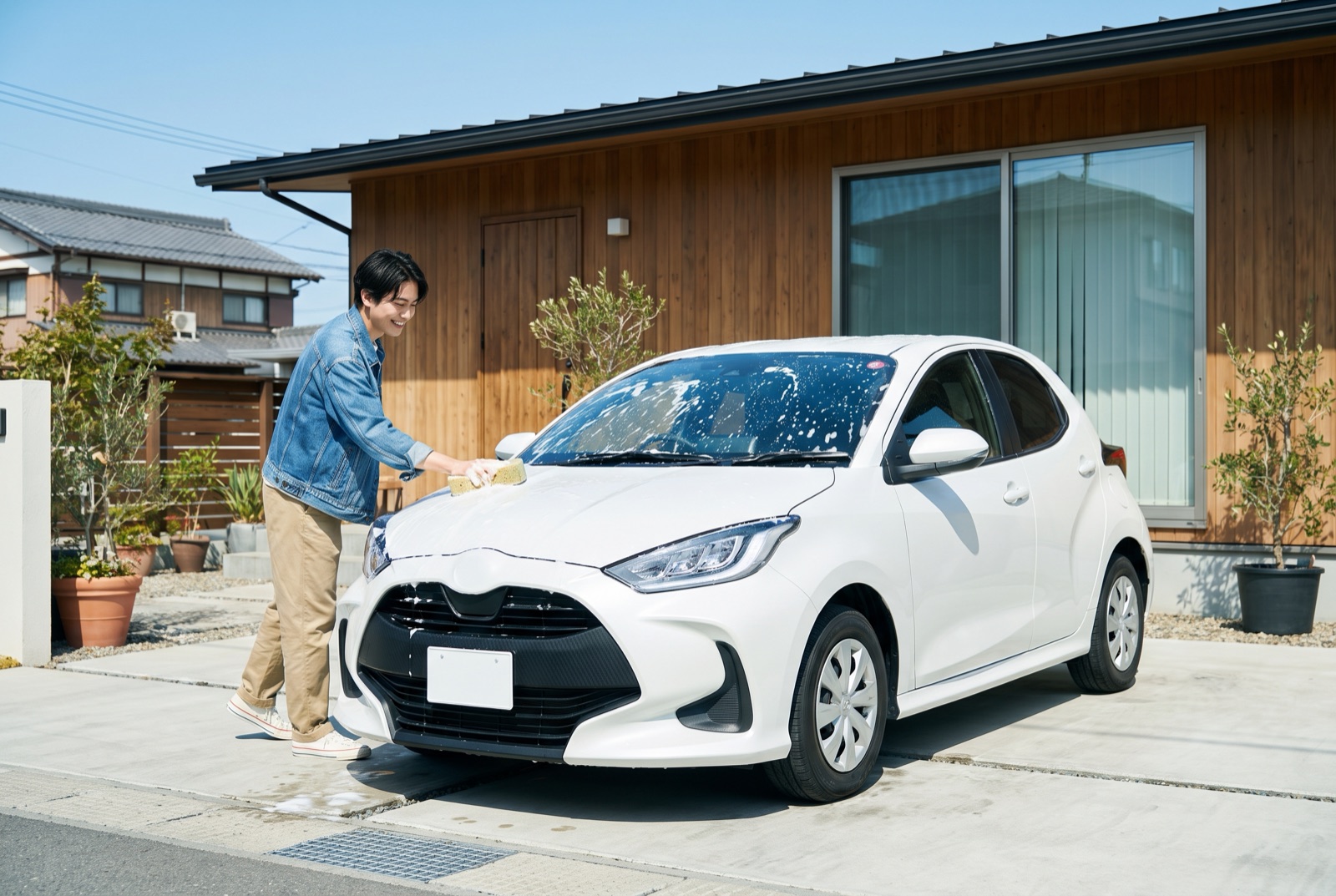 晴れた日に自宅の駐車スペースで手洗い洗車をする様子