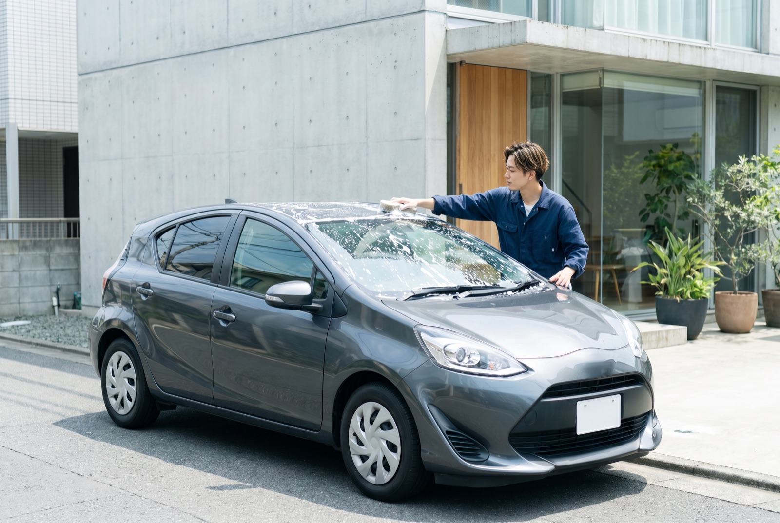 泡をたっぷり使って車を手洗いする男性